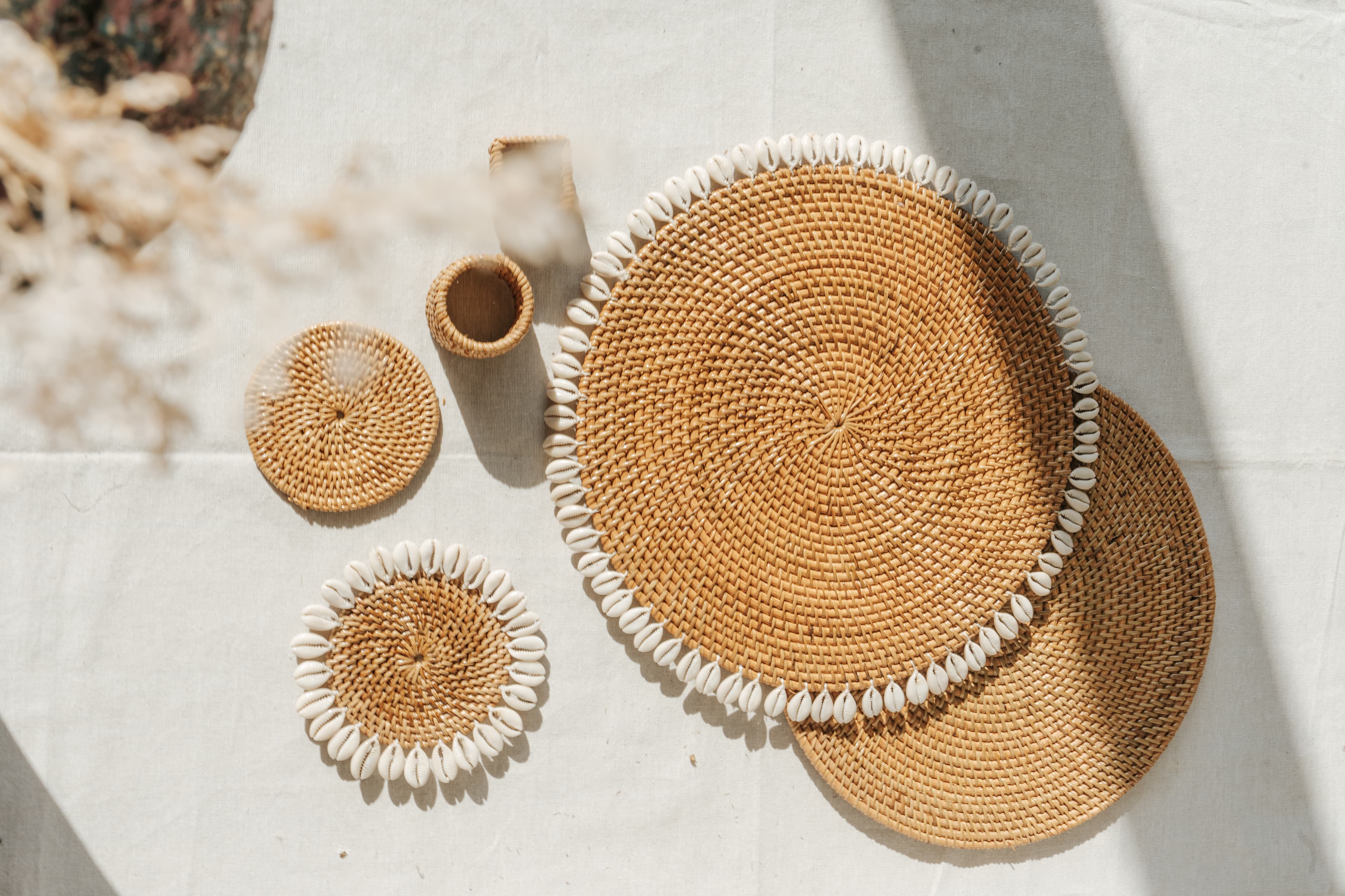 Handwoven rattan pieces with cowrie shells on natural linen